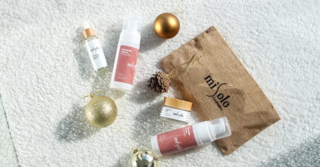 Top view of skincare products with festive ornaments on a white textured surface.