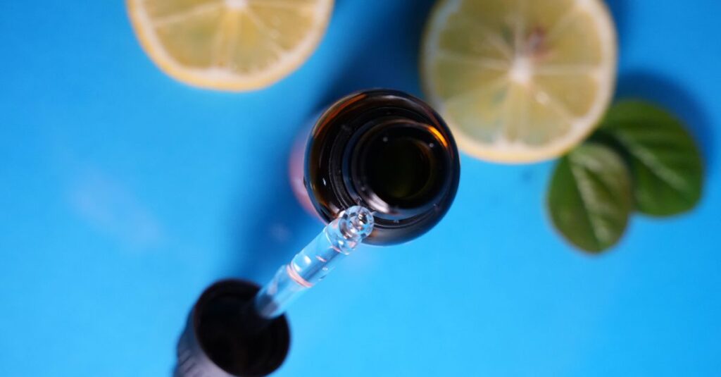Ingredients Close-up of dropper bottle with lemon slices on blue backdrop. Ideal for skincare or wellness themes.
