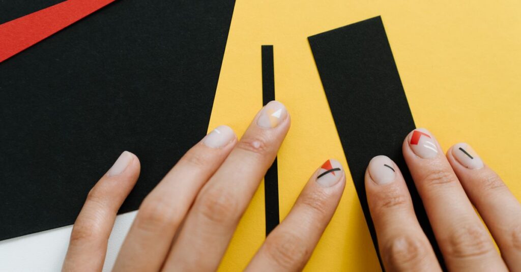 Close-up of modern nail art with geometric shapes on a yellow and black paper collage.