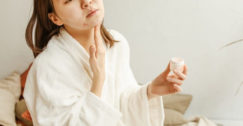 Skincare An adult woman in a bathrobe applies facial cream during her skincare routine indoors.